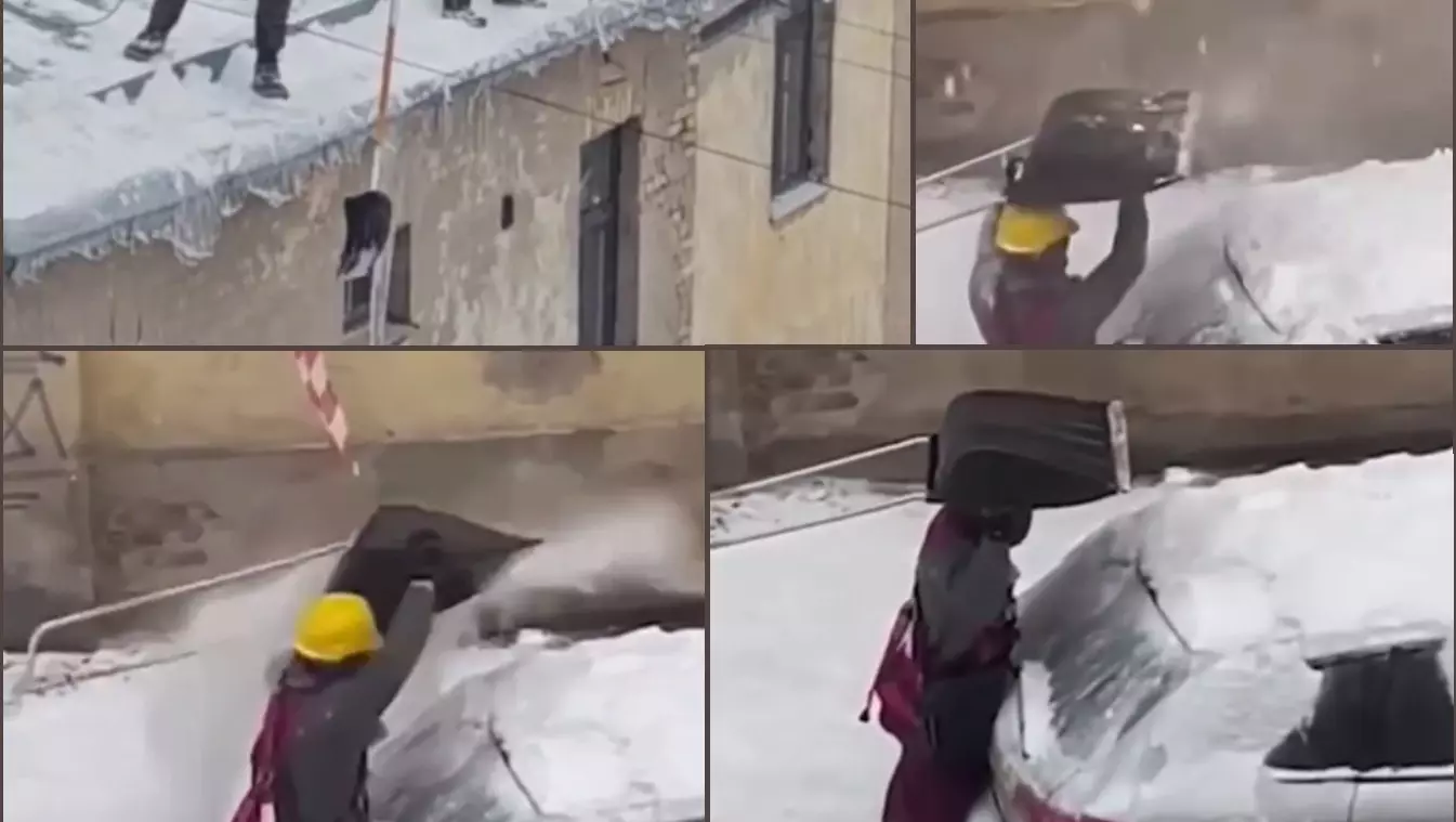 Отважный коммунальщик сбивает лопатой падающую с крыш наледь