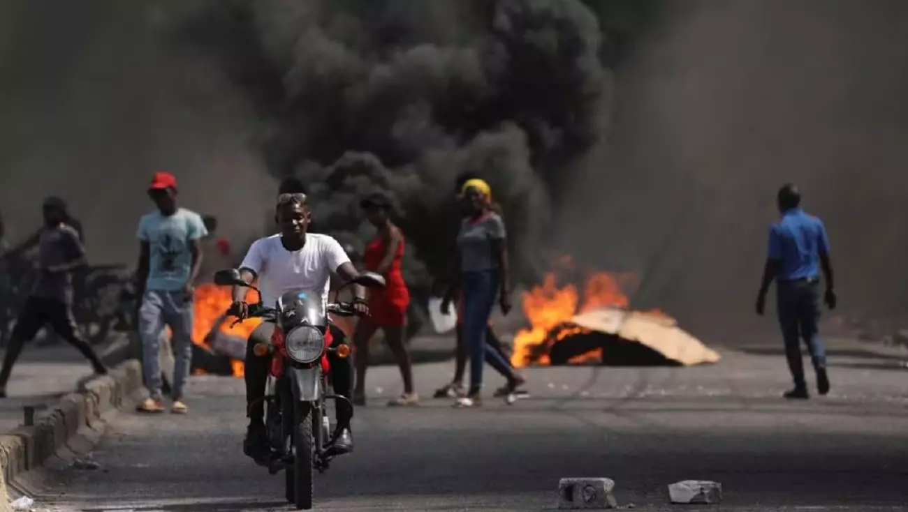 Мужчина проезжает мимо горящей баррикады во время акции протеста в Порт-о-Пренсе, Гаити, 1 марта 2024 года.